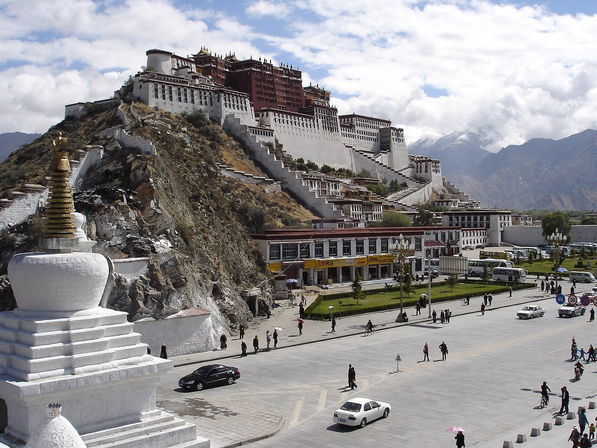 The Potala Palace rising above Lhasa with a white stupa in the foreground