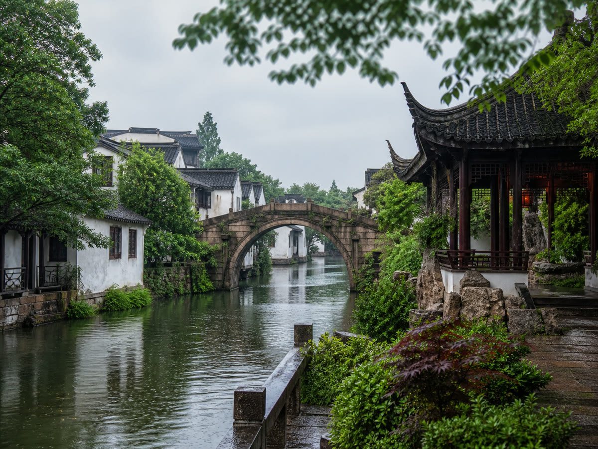 A Suzhou canal lined with whitewashed houses and an arched stone bridge