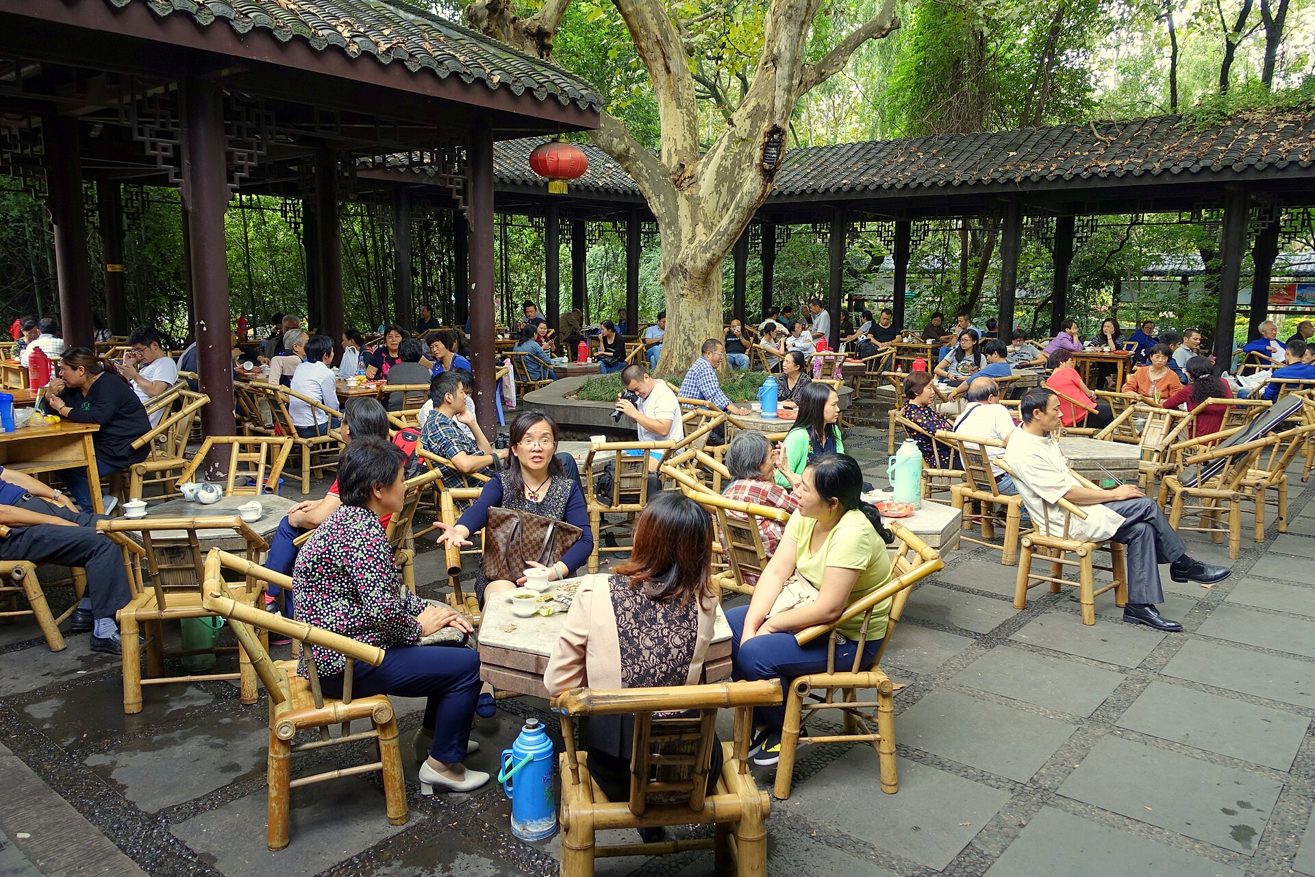 Adults seated on bamboo chairs with tea cups and thermos flasks at a teahouse in Chengdu People's Park in 2015.