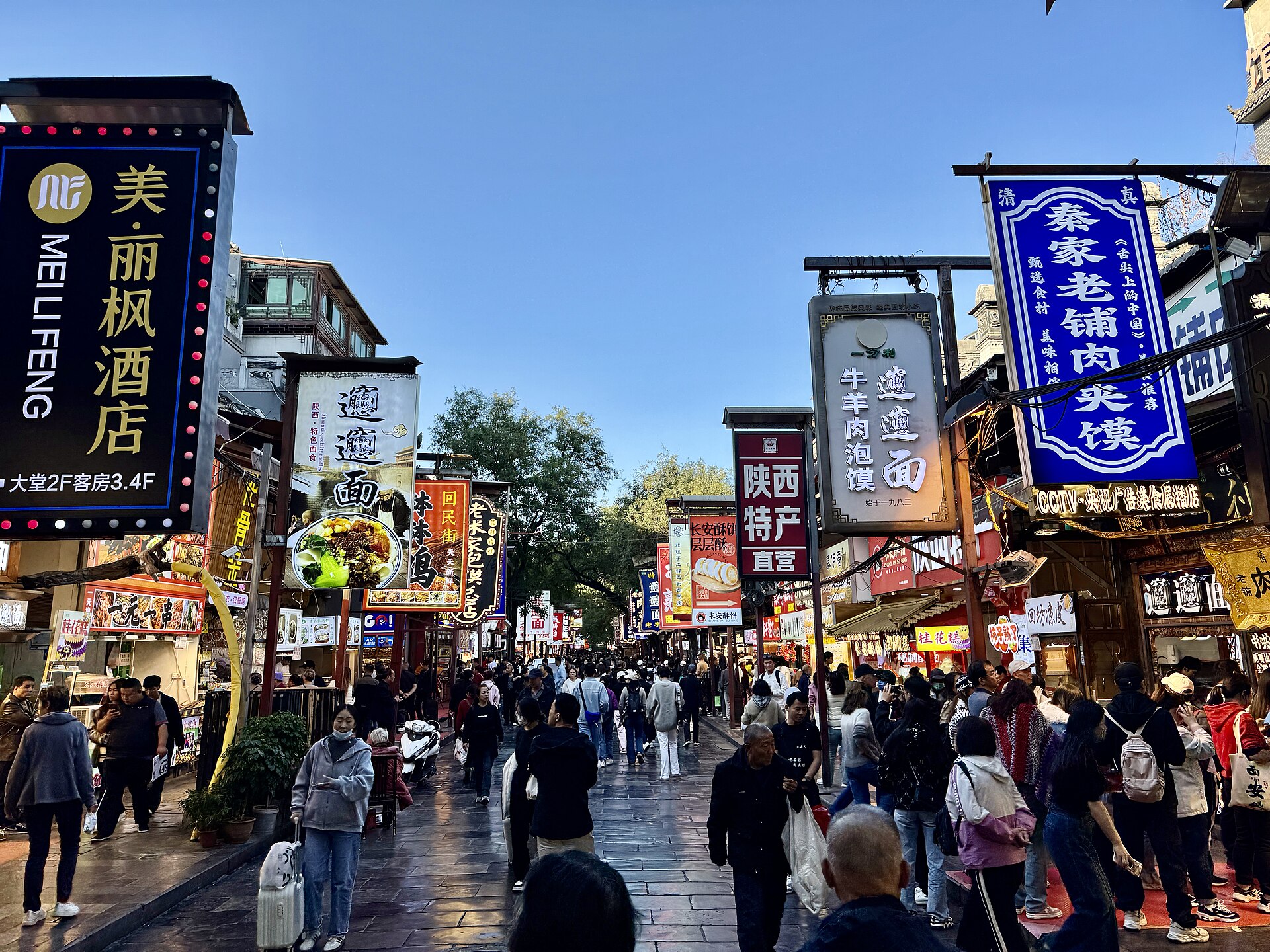 Dense restaurant signs line a crowded daytime section of Beiyuanmen food street in Xi'an.