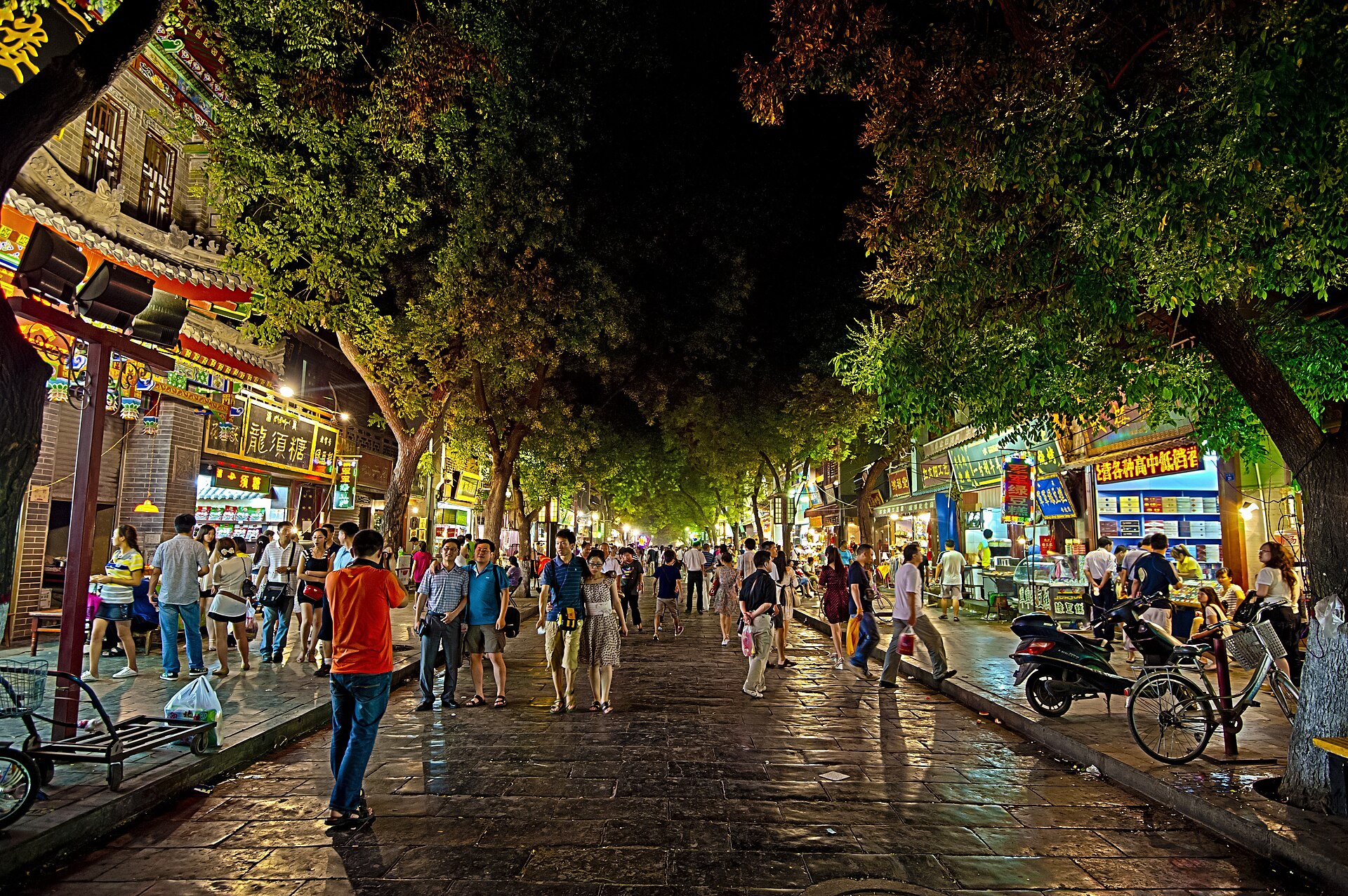 Visitors walk between brightly lit food shops in Xi'an's Beiyuanmen area at night.